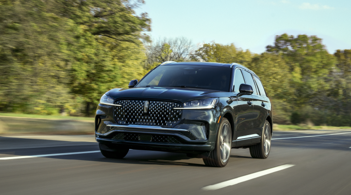 A 2025 Lincoln Black Label Aviator® SUV is being driven down a road lined with trees. | Planet Lincoln Love Field in Dallas TX
