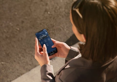 A person is shown interacting with a smartphone to connect to a Lincoln vehicle via the Lincoln Way® App. | Planet Lincoln Love Field in Dallas TX