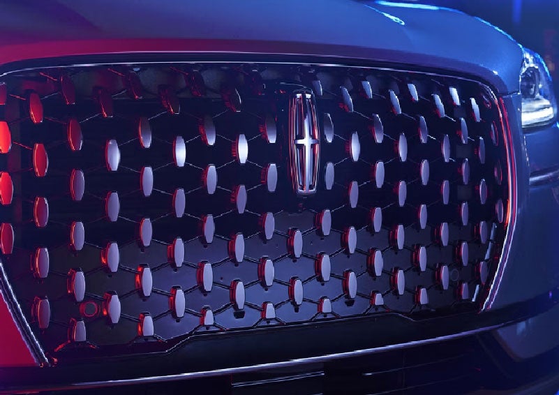 The grille of a 2025 Lincoln Corsair® SUV reflects neon light at night. | Planet Lincoln Love Field in Dallas TX