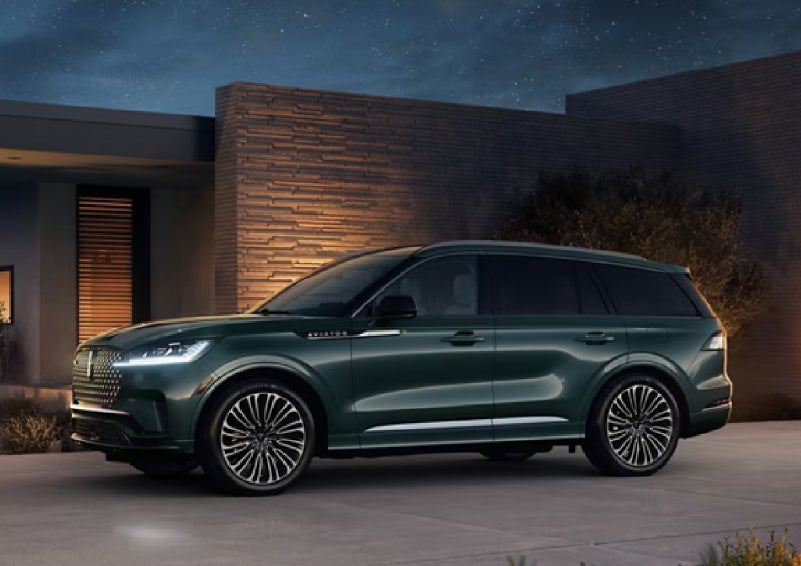 A green 2027 Lincoln Aviator® SUV is parked outside a contemporary home. | Planet Lincoln Love Field in Dallas TX