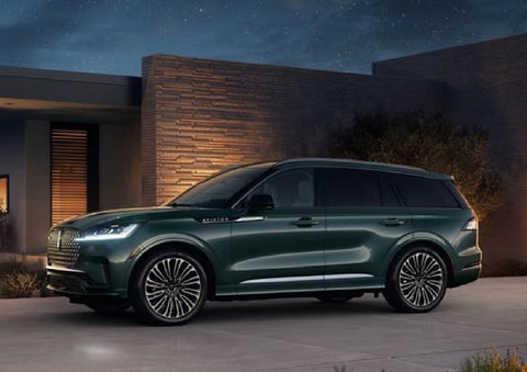 A green 2027 Lincoln Aviator® SUV is parked outside a contemporary home. | Planet Lincoln Love Field in Dallas TX
