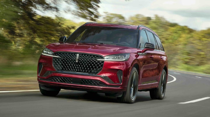 A 2027 Lincoln Aviator® SUV is being driven on a country road | Planet Lincoln Love Field in Dallas TX