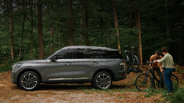 A father and son load e-bikes on a bike rack attached to a 2027 Lincoln Aviator® SUV. | Planet Lincoln Love Field in Dallas TX