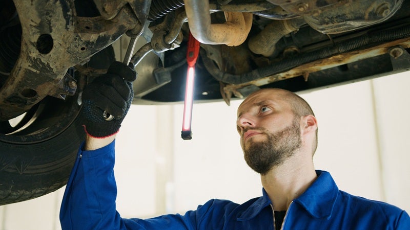 Vehicle service tech inspecting underneath a vehicle